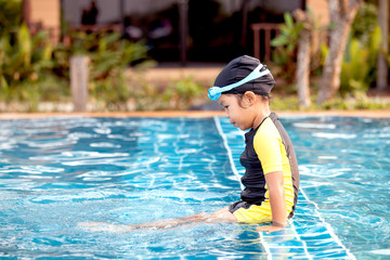 Naklejka premium Cute asian little girl having fun to swim in swimming pool