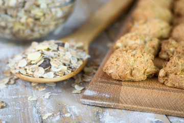 Muesli on wooden spoon and fresh biscuits with cereals on a wooden table.