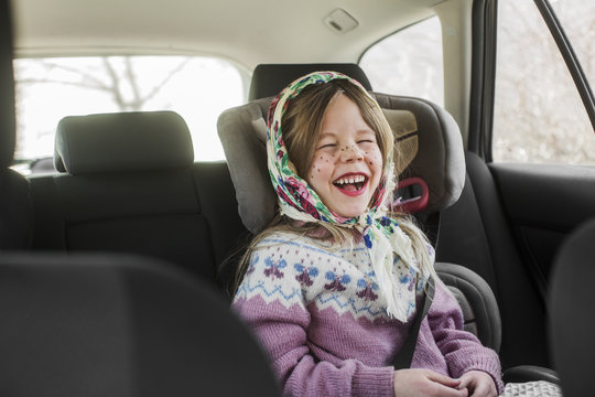 Sweden, Girl (4-5) dressed up as Easter witch wearing headscarf laughing in car