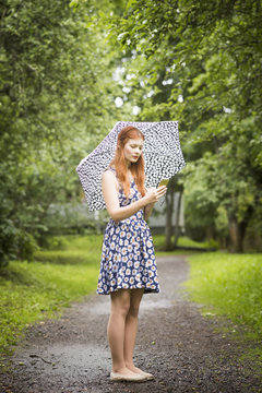 Finland, Pirkanmaa, Tampere, Woman wearing floral dress standing with umbrella in park
