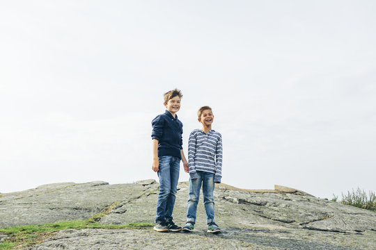 Sweden, Blekinge, Karlskrona, Boys (8-9) standing on asphalt mound and laughing