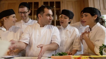 Portrait smiling professional chef with happy young trainees in cookery school