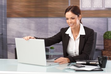 Happy businesswoman shutting down laptop