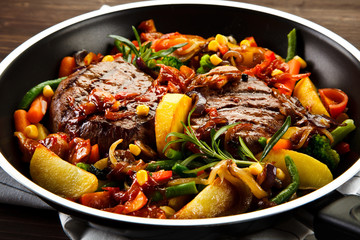 Roast steak with vegetables served on frying pan