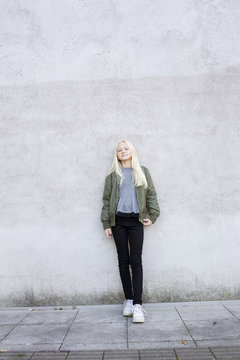 Sweden, Portrait of girl (12-13) standing against concrete wall