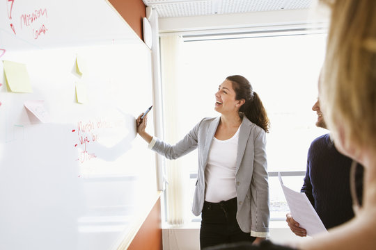 Sweden, Businesswoman standing at board and laughing during business meeting