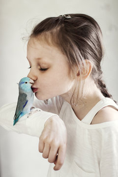 Sweden, Girl (8-9) kissing blue pet bird
