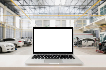 laptop on wooden table with blurred car service centre background
