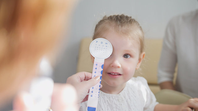Check up of eyesight in child's ophthalmology - optometrist diagnosis little girl