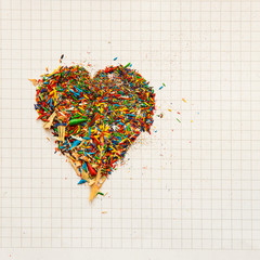 Multicolored pencil shavings on a white squared paper background