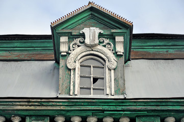 Small ancient wooden arched attic window on the green roof. Close up.