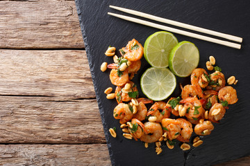 Asian food: sauteed shrimp with peanuts, lime and greens closeup. horizontal top view