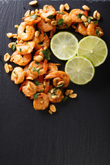 Spicy sauteed of shrimp, peanuts, lime and herbs closeup. Vertical top view