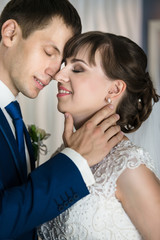 Groom and bride are kissing in hotel interior