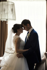 Groom and bride are kissing in hotel interior