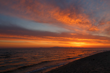 Spring orange dawn on the shore of the calm sea during the tide.