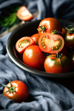 Black prince heirloom tomatoes in a black bowl with fresh rosemary sprig
