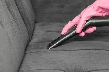 Professionally nozzle releasing sofa from dust. Upholstered furniture. Early spring cleaning or regular clean up.