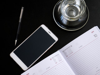 Modern dark office Desk computer, mobile phone,Notepad, pen and Cup. The view from the top