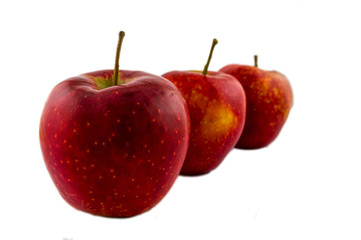Three red ripe apples stand one after another. Juicy red apples isolated on white background.