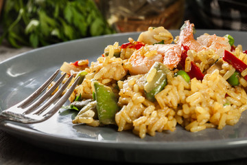 Traditional seafood paella with shrimp, fish and chicken seved in plate.