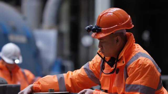 Male & female engineers in power plant turning a valve on pipeline