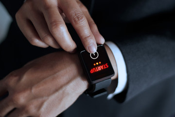 Businessman press button startup on smart watch in hand, dark background
