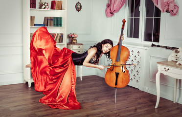 Beauty in mid-air. Full length studio shot of attractive young woman in orange dress hovering in air and playing the cello © oksana_bondar