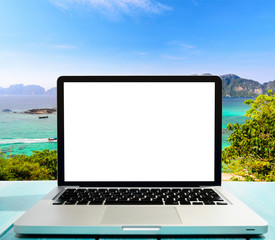 Modern laptop on blue wooden table with blank screen at tropical beach