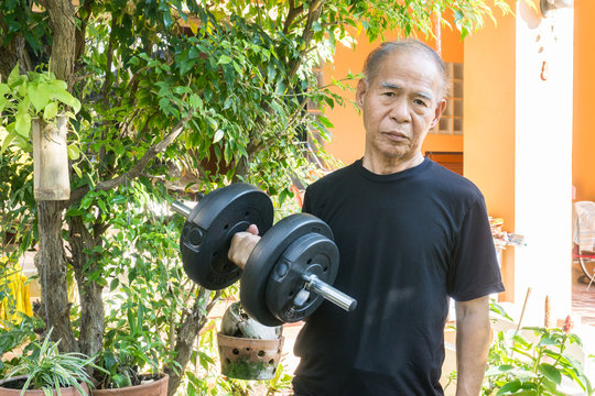 Old asia man with dumbbells. Person doing exercise outdoor. Strengthen the muscles. Your health is priceless. Hard work for a healthy lifestyle concept.