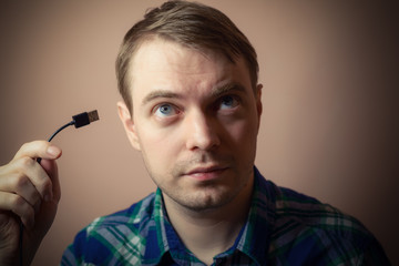 Young man with computer cable in his hand. Selective focus.