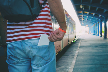 Man holding cellphone in pocket on the train station.