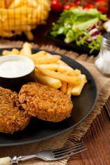 Serving of falafel and chips served on a black plate with sauce.