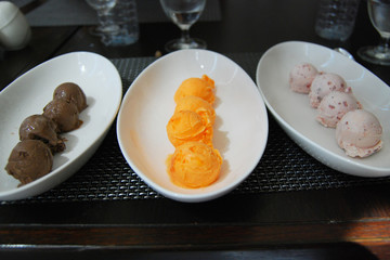 Sixteen scoops of ice cream (Chocolate , Orange sherbet and Strawberry flavors)