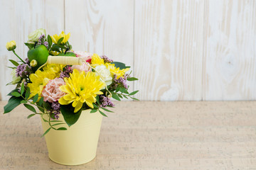 Composition of fresh flowers in a bucket on a wooden background. Copyspace