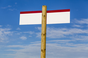 Wooden post with sign, white copyspace and blue sky.