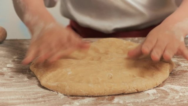 Girls hands fists crumple the dough on the table closeup.