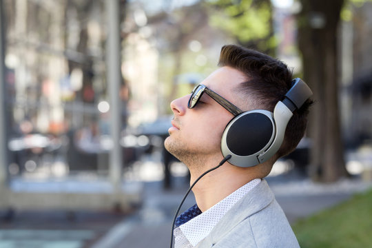 young businessman listening to music with headphones outdoor