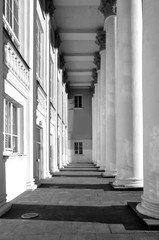 White colonnade of classical building with contrasting shadows. Architectural geometric black and white composition.
