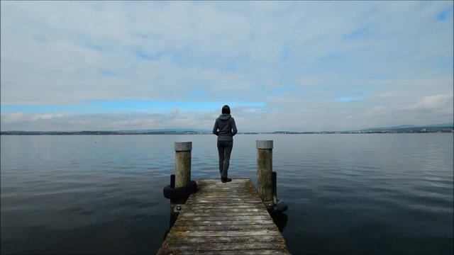 Panorama of the lake Zug. Pier in the foreground. Overcast.  A woman is standing by the lake.