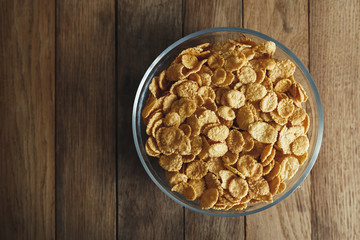 Cornflakes in bowl on the wooden table