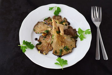 Fried Oyster mushrooms with garlic, parsley and balsamic glaze in a white plate on a black abstract background. Healthy concept