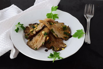 Fried oyster mushrooms with garlic, parsley in a balsamic glaze on a black background. Healthy eating concept.