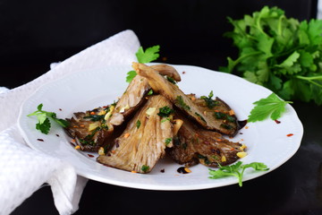 Fried oyster mushrooms with garlic, parsley in a balsamic glaze on a black background. Healthy eating concept.