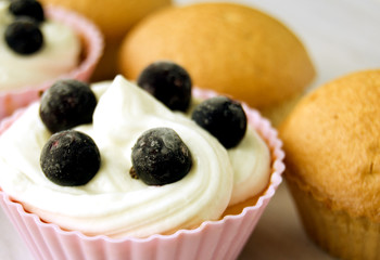 Cakes with cream, decorated with berries, cupcakes. Selective focus