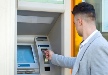 young business man inserting credit card to atm outdoor