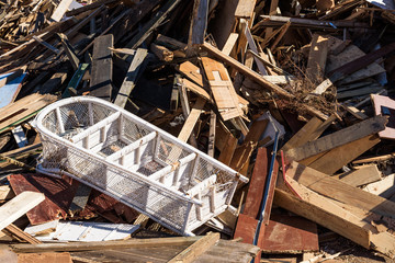 Trashed white rattan shelf in a pile of sorted wooden debris.