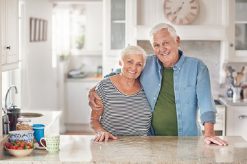 Smiling senior couple content at home in their kitchen