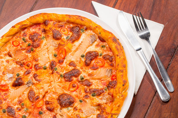 Salmon pizza on a wooden table
