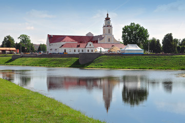 Fototapeta na wymiar Old Town Hall in Orsha, Belarus. Tower in Baroque style with red roof reflected in water.